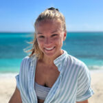 Kat standing on the fish dock holding a wahoo fish the same height as her.